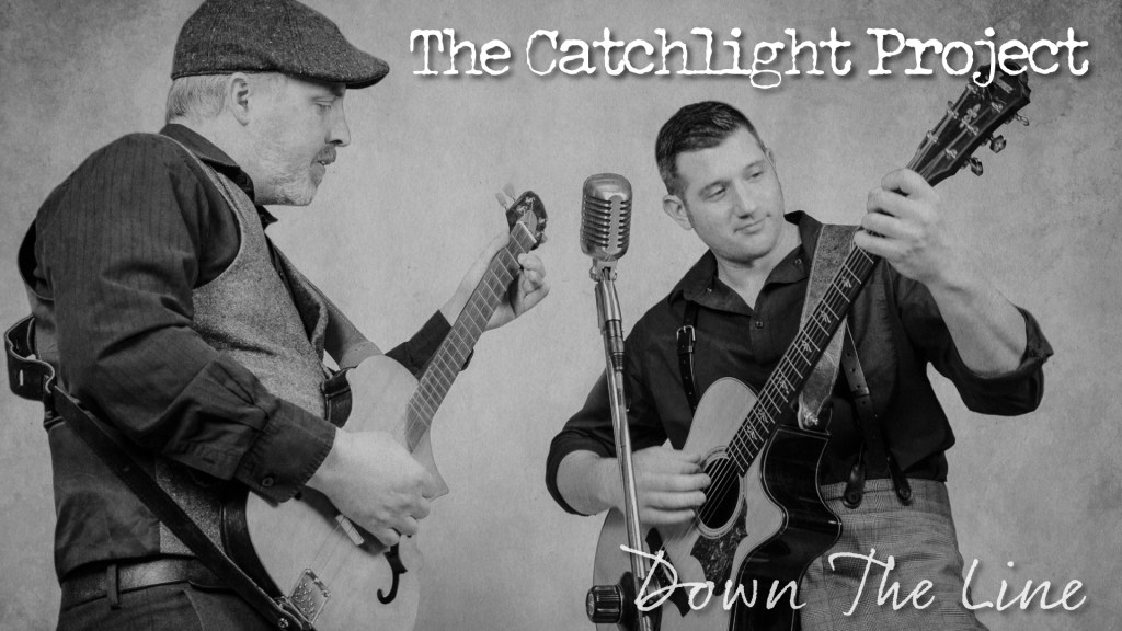 Shane Young and Evan Hinshaw playing guitars around a single microphone.